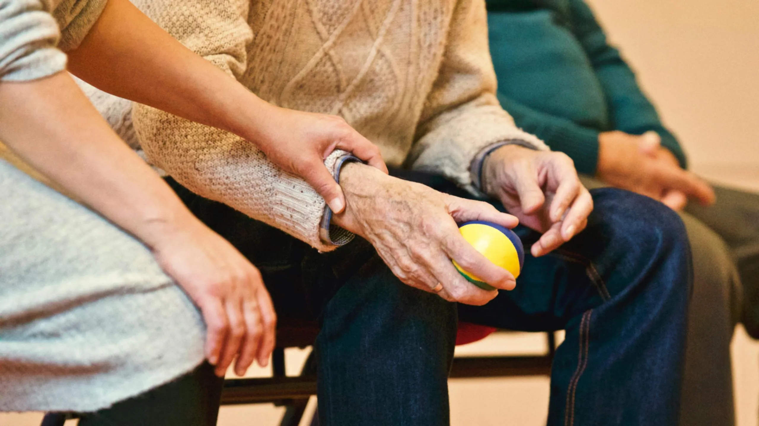 Betreuerin hält einen Therapieball vor einem Senior – Pflegephilosophie Medican Life 24